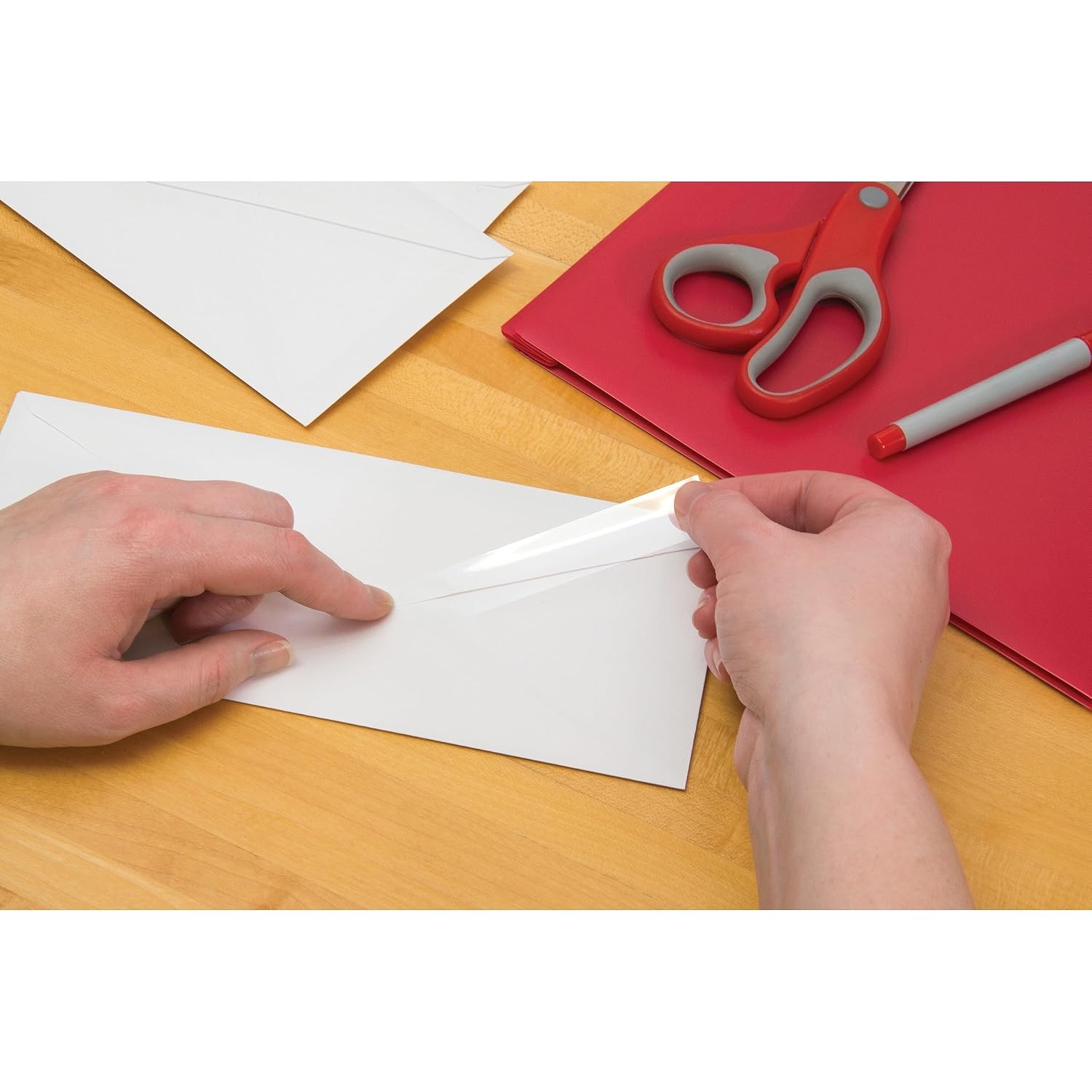 Hands align a strip of tape over a tear in white paper