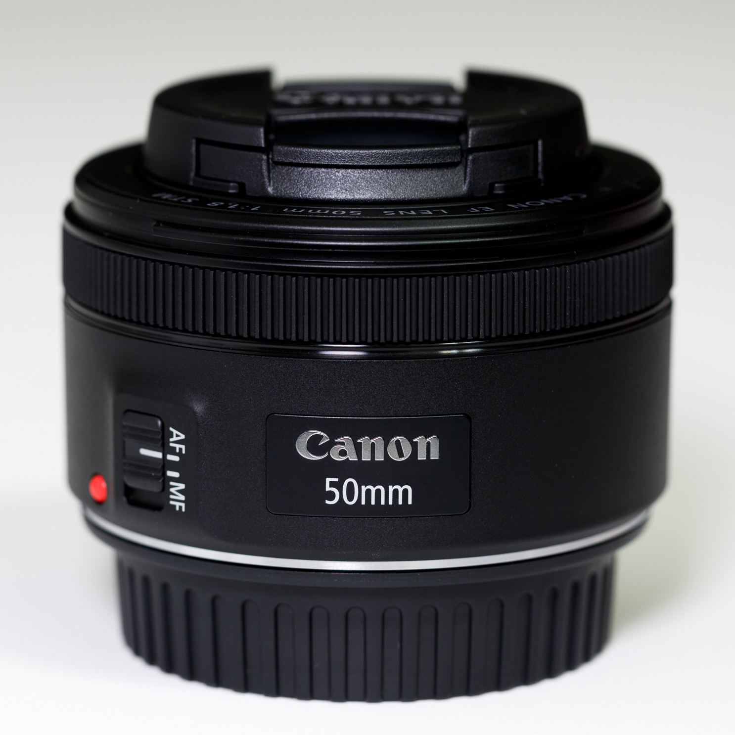 Black Canon EF50mm f/1.8STM lens with caps, showing its model ring and AF/MF switch.
