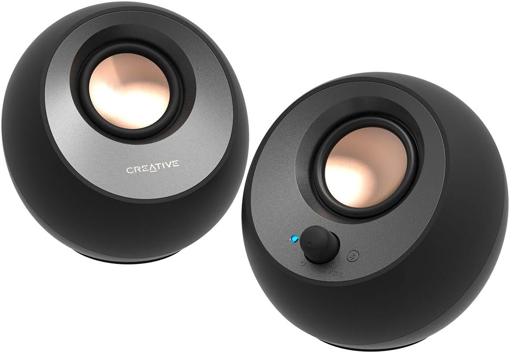 Black Creative Pebble V3 pair with copper-colored drivers and right-side volume and source controls
