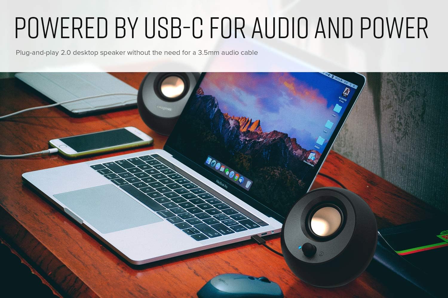 Supplier photograph of black Pebble V3 speakers on either side of a laptop with USB audio text above