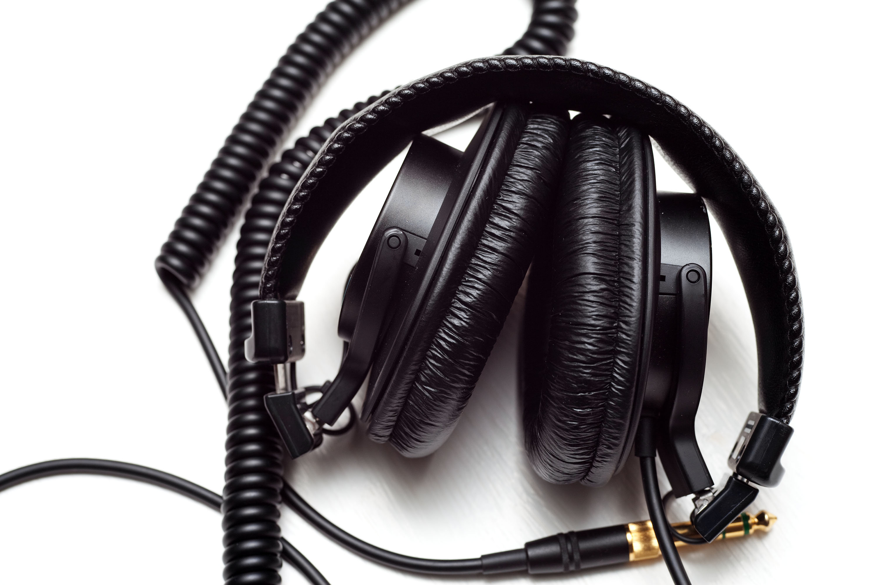 Sony MDR-7506 headphones folded inward, with both padded earcups inside the headband and the coiled cable beside them.