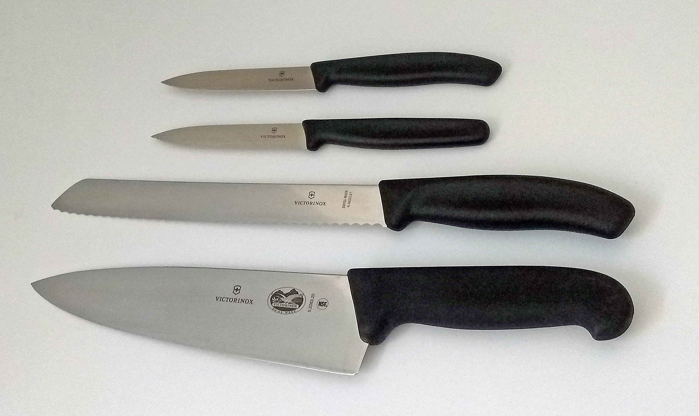 四把刀具摆放图底部的 Victorinox Fibrox 5.2063.20，展示宽阔平刃刀身。