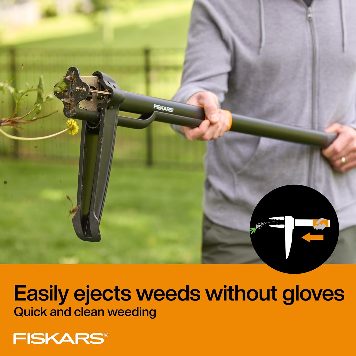 A hand operates the orange sliding ejector on the Fiskars four-claw weeder while the claw head releases a weed andsoil,in an original product-gallery photograph