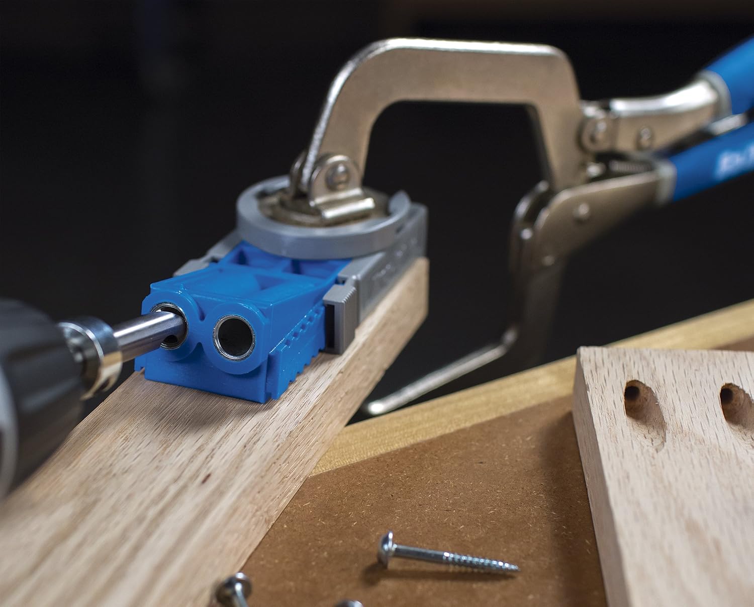 Kreg R3 clamped to a wooden board with a drill bit entering one steel guide