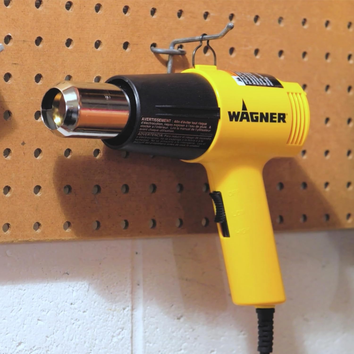 Wagner HT1000 用机身上方的金属挂环挂在洞洞板挂钩上,手柄和电线位于下方。