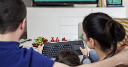 在沙发上使用 Logitech K400 Plus 控制连接电视的电脑