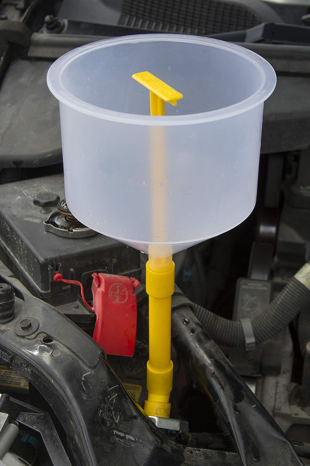 Translucent Lisle 24680 funnel on a yellow straight extension and elbow in an engine bay, with the yellow stopper visible inside.