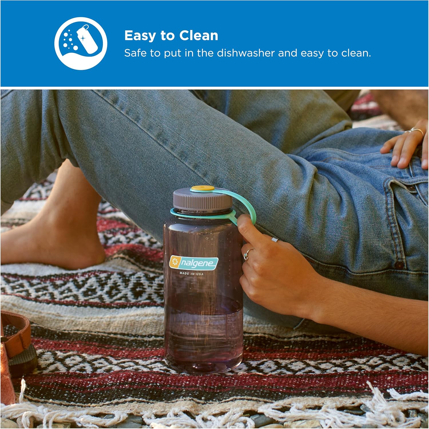 A hand holds the turquoise tether on an Aubergine Nalgene wide-mouth water bottle